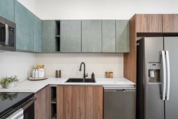 Rochester Hills apartment for rent - A modern kitchen with a black refrigerator and wooden cabinets.
