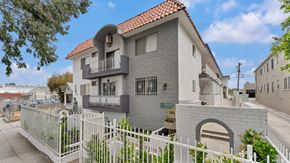 Los Angeles apartment for rent - A grey house with a red roof and a white fence in front.