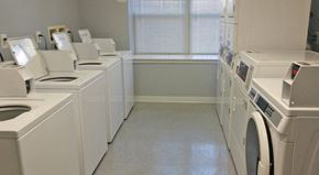 Philadelphia apartment for rent - a washer and dryer room with a row of washing machines and a window