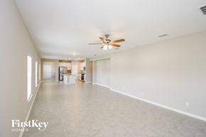 Yulee house for rent - an empty living room with a ceiling fan and a large tile floor