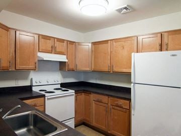 Manalapan apartment for rent - a kitchen with white appliances and wooden cabinets