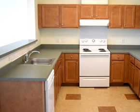 Perth Amboy apartment for rent - an empty kitchen with wooden cabinets and white appliances