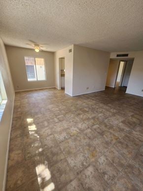 Tucson house for rent - an empty living room with tile floors and a ceiling fan