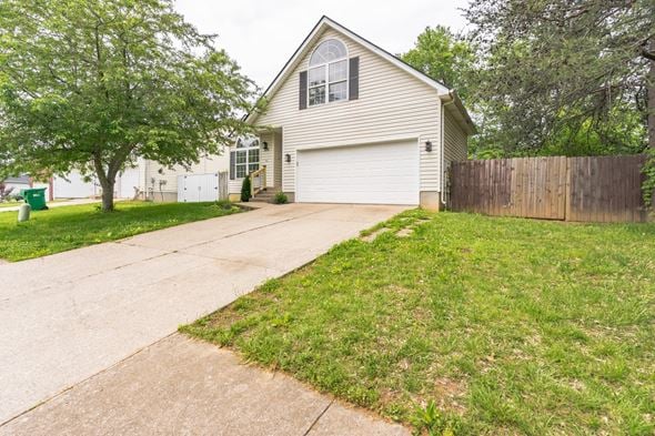 Louisville house for rent - a white house with a driveway and a yard with grass and trees