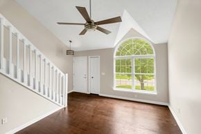 Louisville house for rent - an empty living room with a large window and a ceiling fan