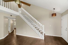 Louisville house for rent - an empty living room with a staircase and a ceiling fan