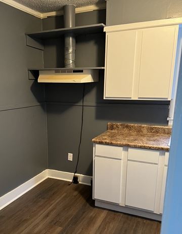 Clarksdale house for rent - a kitchen with white cabinets and a counter top and a exhaust fan