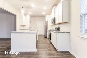 Greenville house for rent - a white kitchen with white cabinets and a wood floor