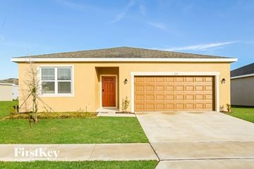 Bartow house for rent - a yellow house with a garage door and a lawn
