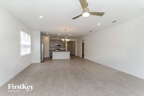 Bartow house for rent - A spacious, empty room with a ceiling fan and a chandelier.
