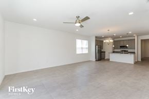 Bartow house for rent - A spacious empty room with a fan and a kitchen in the background.