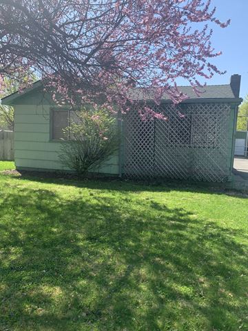 Coeur D Alene house for rent - a small green house with a pink flowering tree in front of it