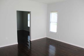 Petal house for rent - an empty living room with hard wood floors and a window