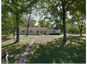 Cincinnati house for rent - A white house is surrounded by trees in a grassy area.