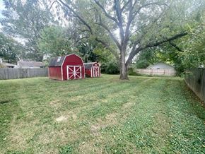 Clarksville apartment for rent - A red barn with a white cross is in the foreground of a grassy field.