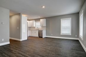 Seattle apartment for rent - an empty living room with a kitchen with white cabinets