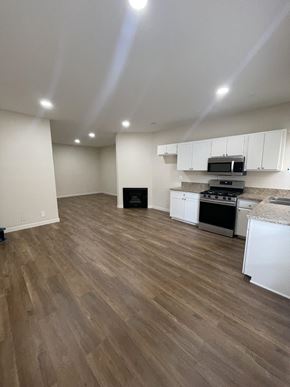 N. Hollywood apartment for rent - an empty kitchen and living room with wood flooring and white cabinets