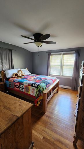 Kingsport house for rent - A bedroom with a bed, wooden dresser, and a ceiling fan.