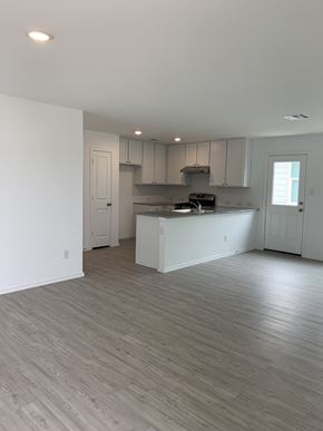 San Antonio house for rent - an empty living room and kitchen with white walls and wood flooring