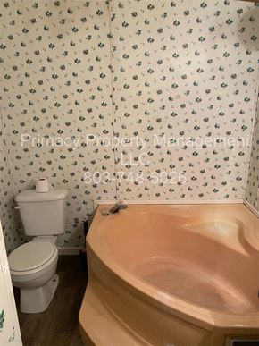 Andrews house for rent - A white toilet sits next to a bathtub in a bathroom with floral wallpaper.