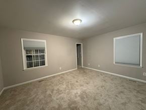 Garner house for rent - A room with carpeted floor, a window with blinds, and a door.
