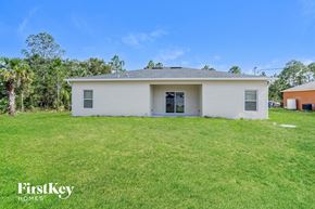 Palm Bay house for rent - A white house with a black door is surrounded by a grassy lawn.