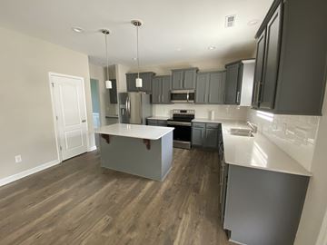 Raeford house for rent - A kitchen with a white counter top and wooden floors.