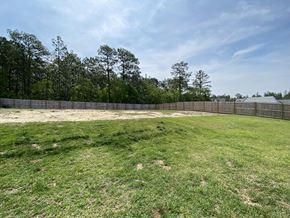 Raeford house for rent - A large, grassy field with a fence and trees in the background.