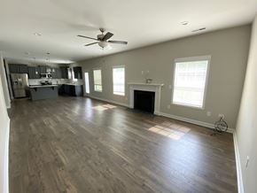 Raeford house for rent - A spacious living room with wood flooring and a ceiling fan.
