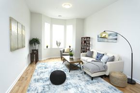 Aberdeen apartment for rent - A living room with a white couch, a black ottoman, and a blue rug.