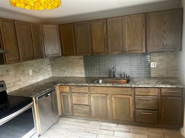 Garner house for rent - A kitchen with wooden cabinets and a granite countertop.