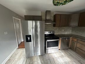 Garner house for rent - A kitchen with a stainless steel refrigerator and wooden cabinets.