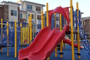 Jersey City apartment for rent - A red slide on a playground with a blue and yellow structure.