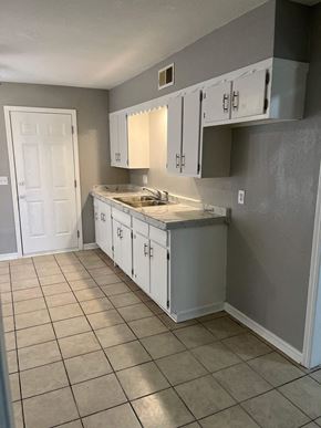 Oklahoma City house for rent - an empty kitchen with white cabinets and a tiled floor