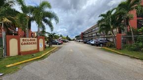 Mangilao apartment for rent - A road leading to a red building with the sign "Belair Gardens" on it.