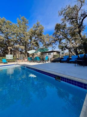 Austin apartment for rent - a swimming pool with chairs and umbrellas next to a resort style pool