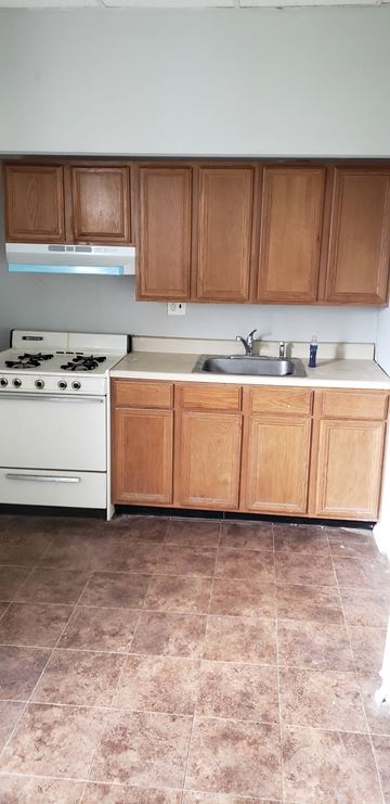 Philadelphia apartment for rent - a kitchen with a stove and a sink and wooden cabinets