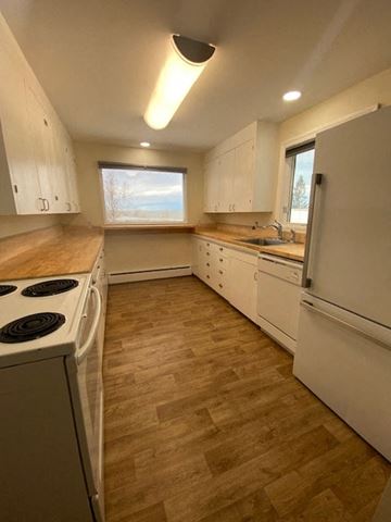 Anchorage apartment for rent - A kitchen with white cabinets and a wooden floor.