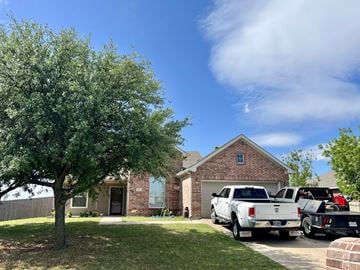 Ponder house for rent - A house with a tree in front and two trucks parked in the driveway.