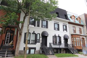 Montreal apartment for rent - a white house with black windows and a tree in front of it