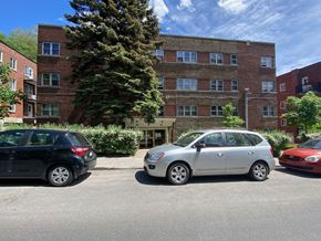 Montreal apartment for rent - a parking lot in front of a brick building with cars parked in front