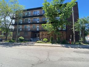 Montreal apartment for rent - an apartment building with a street and trees in front of it