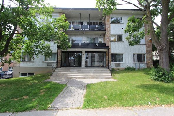Lachine apartment for rent - the front of an apartment building with a lawn and trees