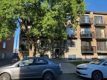 Montreal apartment for rent - an apartment building with two cars parked in front of it