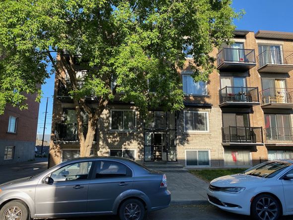 Montreal apartment for rent - an apartment building with two cars parked in front of it