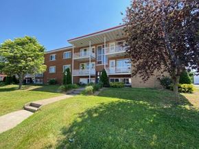 Granby apartment for rent - an apartment building with a green lawn and trees