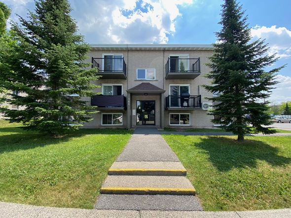Granby apartment for rent - the front of an apartment building with a sidewalk and trees