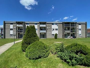 Granby apartment for rent - an apartment building with green grass and trees in front of it