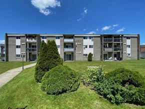 Granby apartment for rent - an apartment building with green grass and trees in front of it