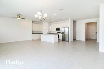 Kissimmee house for rent - a large white kitchen with white cabinets and a stainless steel refrigerator